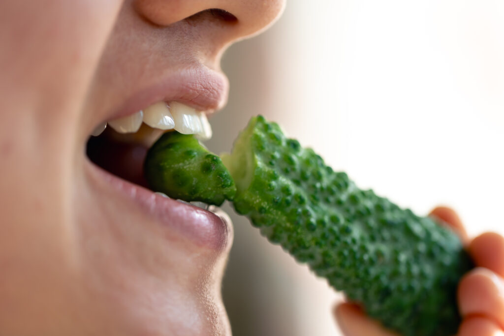 detailed shot woman eats fresh cucumber