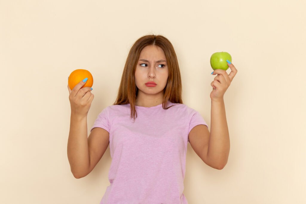 front view young attractive female pink t shirt blue jeans holding orange apple