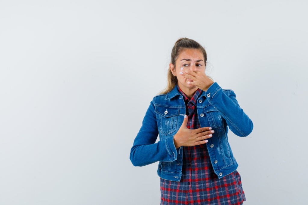 Hinchazón y gases con mal olor 3 young lady shirt jacket pinching nose due bad smell looking disgusted front view